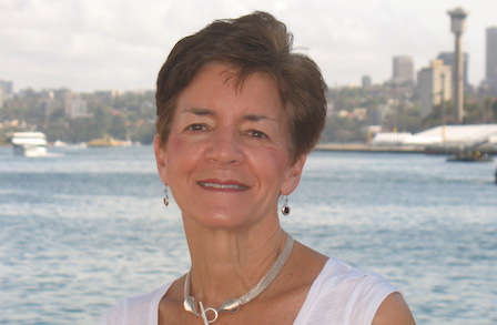 Headshot of Sue Ellen Thompson across the water from a city skyline.